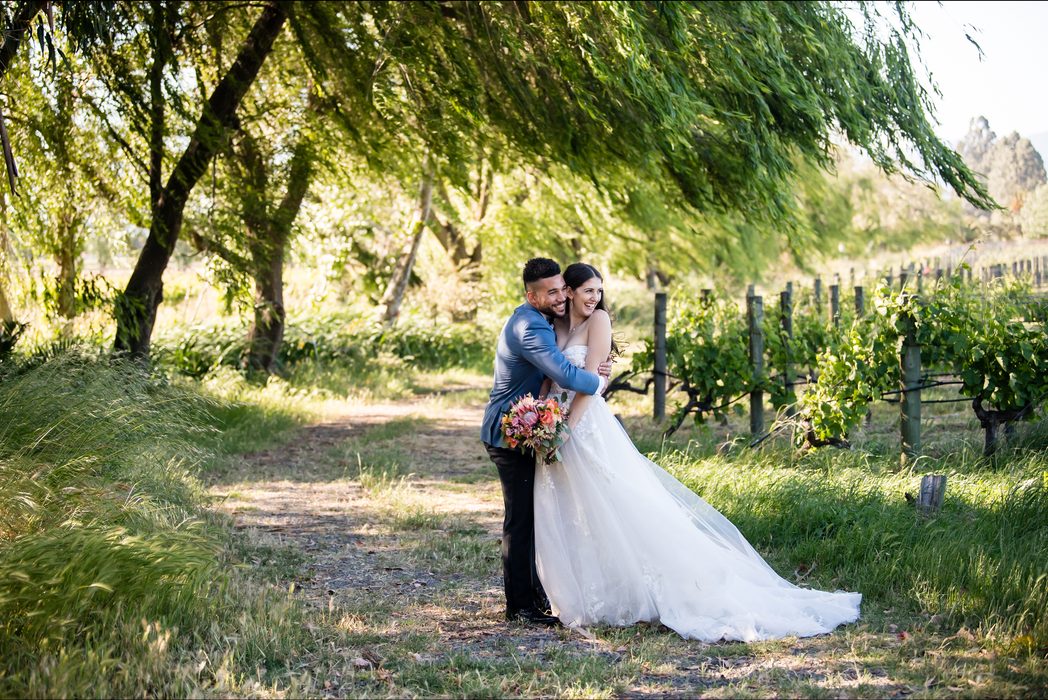 Bride and groom embracing on a tree-lined path